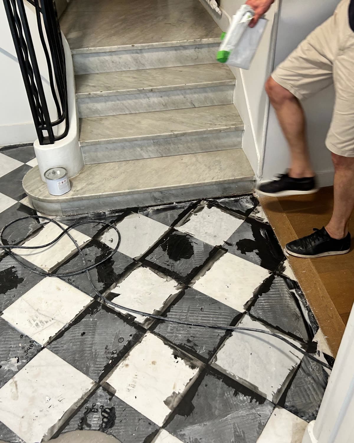 Hall en damier de marbre noir et blanc, sale, pendant le chantier.
