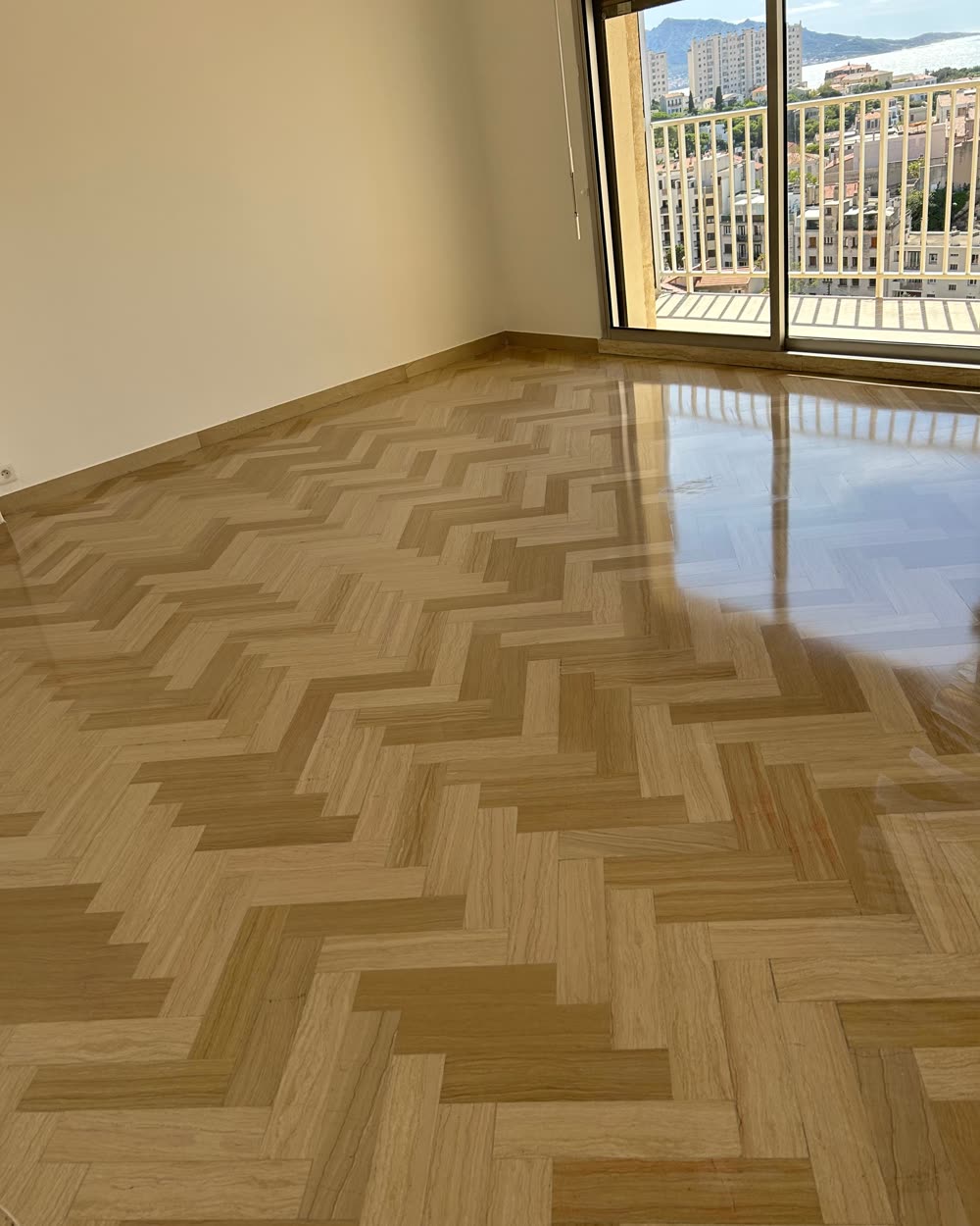 Parquet point de Hongrie clair, poncé et vitrifié, dans un salon avec vue sur la ville.